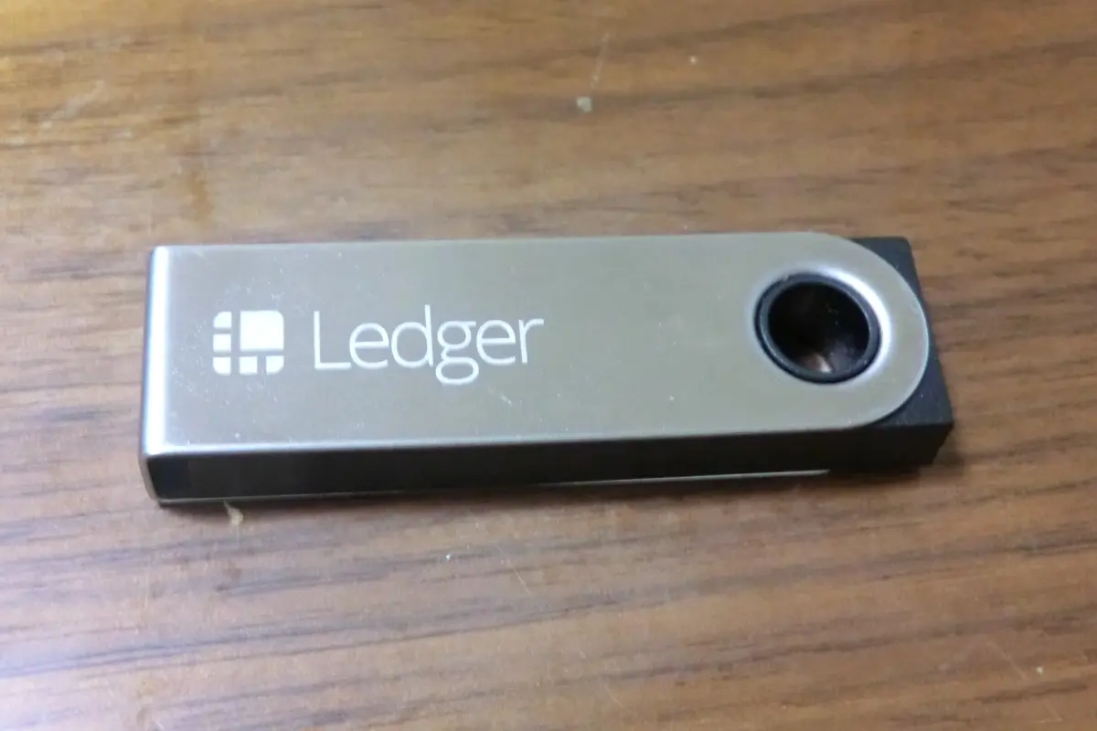 A real Ledger Nano S hardware wallet resting on a wooden surface.